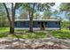 Welcoming blue single-story home featuring a cozy front porch, complemented by lush green grass at 1235 Arapaho Trl, Geneva, FL 32732