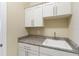 Laundry room with white cabinets, stainless steel hardware, granite countertop, and utility sink at 13755 Benavente Ave, Orlando, FL 32827