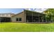 Backyard with a screened-in lanai featuring an outdoor kitchen and a well-maintained lawn at 14831 Yorkshire Run Dr, Orlando, FL 32828