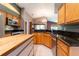 Open kitchen layout with granite countertops, an island with seating, and natural wood cabinetry at 14831 Yorkshire Run Dr, Orlando, FL 32828