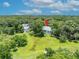 Aerial view of a lovely house, with a red pin on the roof, and a expansive green lawn surrounded by lush trees at 195 River Village Drive, Debary, FL 32713