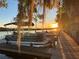 Scenic view of pontoon boats docked at a wooden pier at dusk, with the sun setting and Spanish moss hanging from trees at 195 River Village Drive, Debary, FL 32713