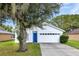 Charming single-story home featuring a blue front door, two-car garage, and mature landscaping at 2308 Donegan Pl, Orlando, FL 32826