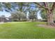 Large backyard with mature trees, lush green grass, a wooden fence, screened-in pool, and playset at 25537 High Hampton Cir, Sorrento, FL 32776