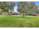 Expansive backyard featuring lush green grass, mature trees, a screened pool, and playset at 25537 High Hampton Cir, Sorrento, FL 32776