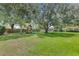 Expansive backyard featuring lush green grass, mature trees, a wooden fence, and a playset at 25537 High Hampton Cir, Sorrento, FL 32776