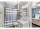 Well-lit bathroom features a white vanity, stylish fixtures, and a shower with a blue and white striped curtain at 25537 High Hampton Cir, Sorrento, FL 32776