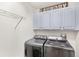 Efficient laundry room featuring modern washer and dryer units with overhead cabinets at 25537 High Hampton Cir, Sorrento, FL 32776