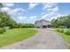 View of the side of a grey home featuring an expansive lawn, gravel driveway, and screened in porch at 32125 Wekiva Pines Blvd, Sorrento, FL 32776