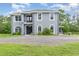 Two story home with grey stucco, manicured landscaping, black front door, and a circular gravel driveway at 32125 Wekiva Pines Blvd, Sorrento, FL 32776
