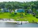 Waterfront property featuring a charming home, private beach, boat dock, and lush greenery at 36607 E Eldorado Lake Dr, Eustis, FL 32736
