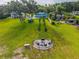 Aerial view of a spacious backyard with a fire pit, landscaping, and waterfront access at 36607 E Eldorado Lake Dr, Eustis, FL 32736