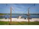 Picturesque sandy beach area with a dock, chairs, and umbrellas for lakeside relaxation at 36607 E Eldorado Lake Dr, Eustis, FL 32736