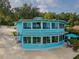 Unique blue two-story home with expansive windows, a patio, and outdoor seating at 36607 E Eldorado Lake Dr, Eustis, FL 32736