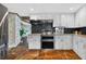 A kitchen features stone floors and white cabinets with granite countertops and black tile backsplash at 36607 E Eldorado Lake Dr, Eustis, FL 32736
