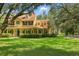 Inviting yellow home with red roof, manicured lawn, covered front porch, and lush landscaping at 4200 Joslyn Ln, Lady Lake, FL 32159