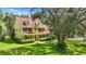 Stunning yellow home with a red roof, wraparound porch, lush lawn, and mature trees offering shade at 4200 Joslyn Ln, Lady Lake, FL 32159