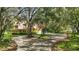 Picturesque yellow home with a red roof, surrounded by mature trees, a circular driveway, and lush greenery at 4200 Joslyn Ln, Lady Lake, FL 32159