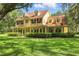 Beautiful yellow home with a red roof, large windows, and a well-maintained front lawn with mature trees at 4200 Joslyn Ln, Lady Lake, FL 32159
