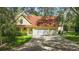 Lovely yellow home with attached garage, a red roof, manicured front lawn, and mature trees at 4200 Joslyn Ln, Lady Lake, FL 32159