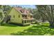 Spacious yellow home with a red roof, large porch, and well-manicured lawn surrounded by mature trees at 4200 Joslyn Ln, Lady Lake, FL 32159