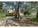 Charming yellow home with a red roof, mature trees, a spacious front yard, and a circular driveway at 4200 Joslyn Ln, Lady Lake, FL 32159