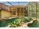 Enclosed pool area featuring natural rock formations, tropical landscaping, and a covered deck overlooking the water at 4200 Joslyn Ln, Lady Lake, FL 32159