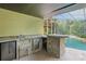 Outdoor bar area with stone countertop, mini fridge, and built-in grill, perfect for poolside entertaining at 4200 Joslyn Ln, Lady Lake, FL 32159