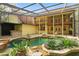 Expansive pool and backyard oasis featuring rock accents, lush greenery, a screened enclosure, and outdoor kitchen at 4200 Joslyn Ln, Lady Lake, FL 32159