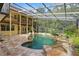 Stunning pool and outdoor area with waterfalls, lush greenery, a screened enclosure, and second-story balcony at 4200 Joslyn Ln, Lady Lake, FL 32159