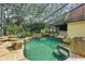 Lushly landscaped pool area featuring rock features, waterfalls, a screened enclosure, and a built-in bar at 4200 Joslyn Ln, Lady Lake, FL 32159