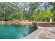 Tranquil swimming pool featuring rock features, waterfall, lush landscaping, and a screened enclosure at 4200 Joslyn Ln, Lady Lake, FL 32159