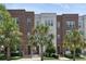 Charming multi-story townhomes with brick and white brick exteriors, complemented by lush landscaping and palm trees at 464 W Plant St, Winter Garden, FL 34787