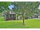 View of the house exterior and screened lanai from backyard with a lush lawn and mature tree at 5929 Hatteras Dr, Port Orange, FL 32127