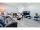 Modern living room with grey wood-look flooring, neutral walls, and comfortable leather seating at 7033 Lakner Way, Orlando, FL 32822