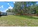 Large backyard with healthy green grass, a new wooden fence, mature shade trees, and an outbuilding in the distance at 7360 Canal Dr, Sanford, FL 32771