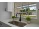 Close up on the modern kitchen sink, white cabinets and countertop, and a window view of the outdoors at 7360 Canal Dr, Sanford, FL 32771