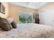 Bright bedroom featuring a neutral color scheme, tray ceiling, and view of outdoor greenery from the window at 7625 Long Island Dr, Kissimmee, FL 34747