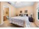 Bedroom showcasing a tray ceiling, wall art, and a view into the adjacent bathroom at 7625 Long Island Dr, Kissimmee, FL 34747