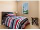 Cozy bedroom with a dark wood headboard, striped bedding, and natural light from the window at 7625 Long Island Dr, Kissimmee, FL 34747