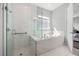 Bright bathroom showcasing a walk-in shower, soaking tub, and white marble-style tile at 7778 Four Seasons Blvd, Kissimmee, FL 34747