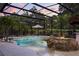 Enjoy this screened pool with tiki bar, rock waterfall, fire feature, and tropical landscaping at 7778 Four Seasons Blvd, Kissimmee, FL 34747