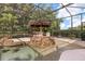 Screened pool area features a tiki bar, built-in grill, rock waterfall, and lush landscaping at 7778 Four Seasons Blvd, Kissimmee, FL 34747