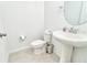 Bright half bathroom with pedestal sink, round mirror, and gray tile flooring, perfect for guests at 832 Longboat Dr, Davenport, FL 33896