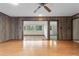 Open living room features hardwood floors, wood paneling, ceiling fan, and lots of natural light at 9601 Ambleside Dr, Windermere, FL 34786
