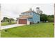 Two-story home with blue exterior, brown garage, lush green lawn, and mature palm trees at 1001 Dampierre Ct, Kissimmee, FL 34759