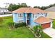 Aerial view of a blue, two-story home with a well-manicured lawn and mature palm trees at 1001 Dampierre Ct, Kissimmee, FL 34759