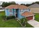 Aerial view of a blue, two-story home with a well-manicured lawn and mature palm trees at 1001 Dampierre Ct, Kissimmee, FL 34759