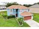 Aerial view of a blue, two-story home with a well-manicured lawn and mature palm trees at 1001 Dampierre Ct, Kissimmee, FL 34759
