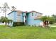 A two-story home with a well-manicured lawn, palm trees, and a painted blue exterior at 1001 Dampierre Ct, Kissimmee, FL 34759